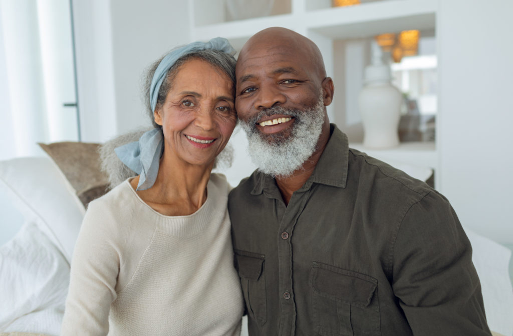 Happy senior couple smiling at camera while being in living room of senior community
