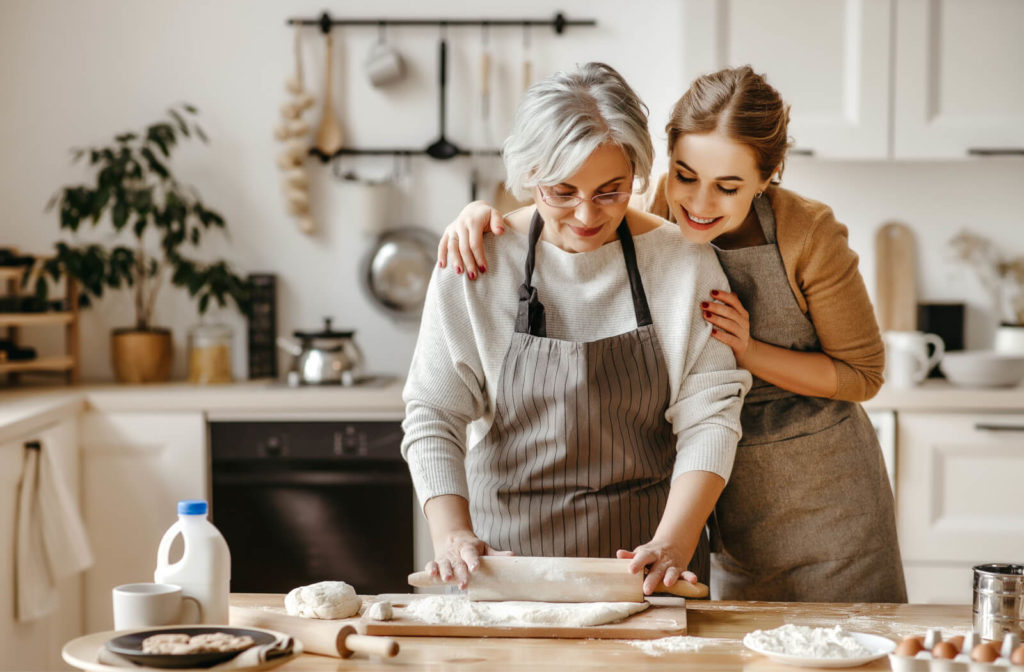 A senior woman with gray hair with her daughter baking together in the kitchen.