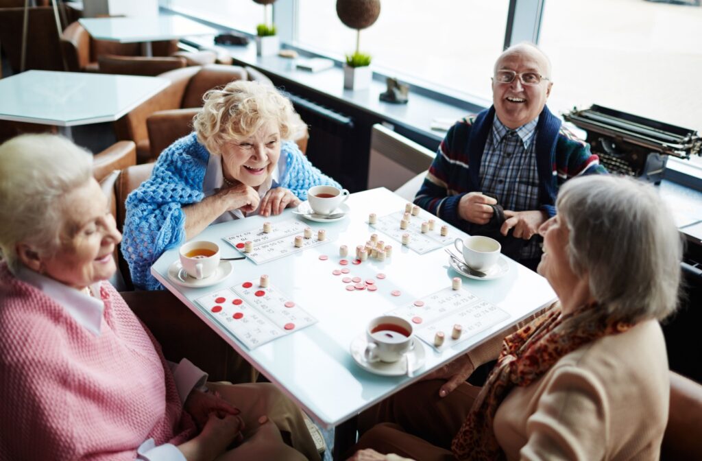 Group of elderly people sitting by table, talking and playing lotto