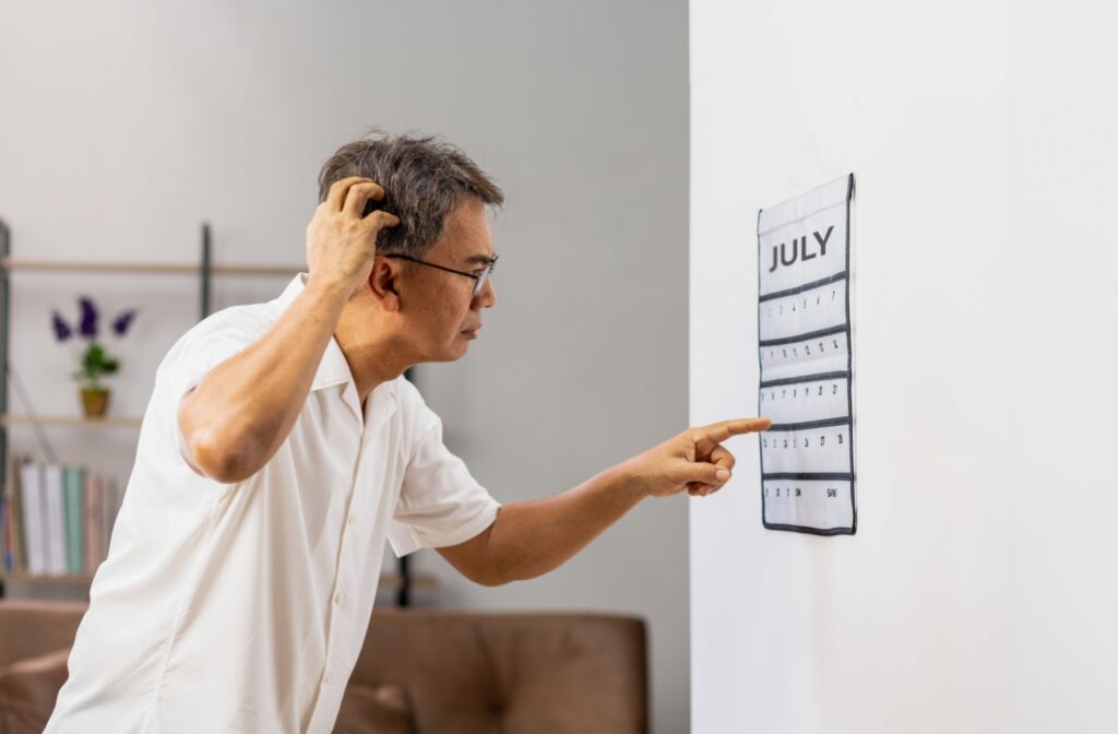 Confused senior man looking at a calendar while trying to remember the date.