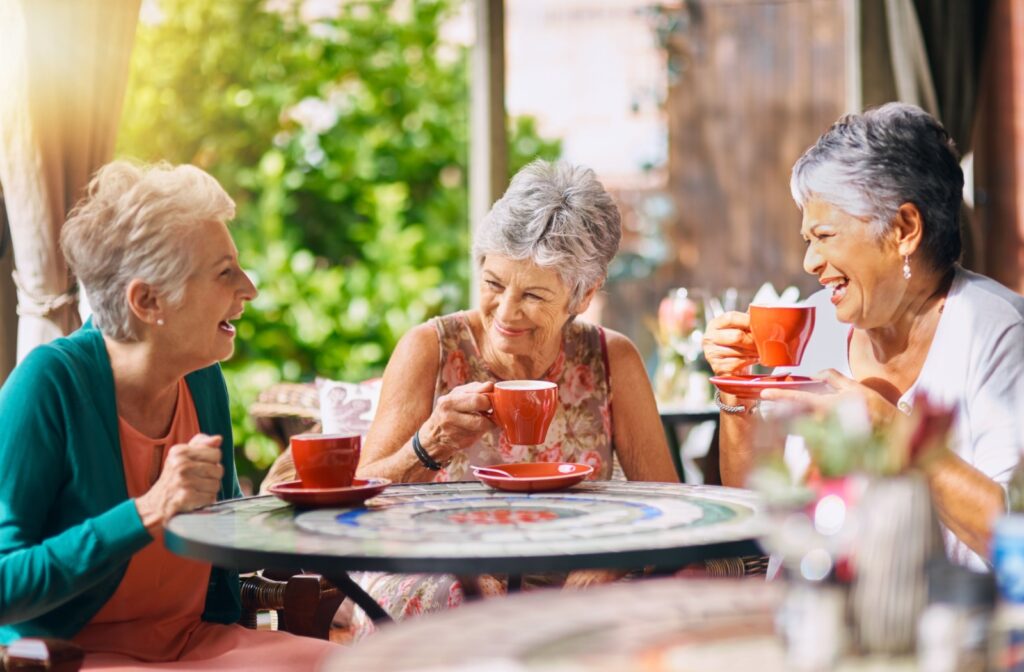 A group of older friends laughing together while enjoying a cup of tea.