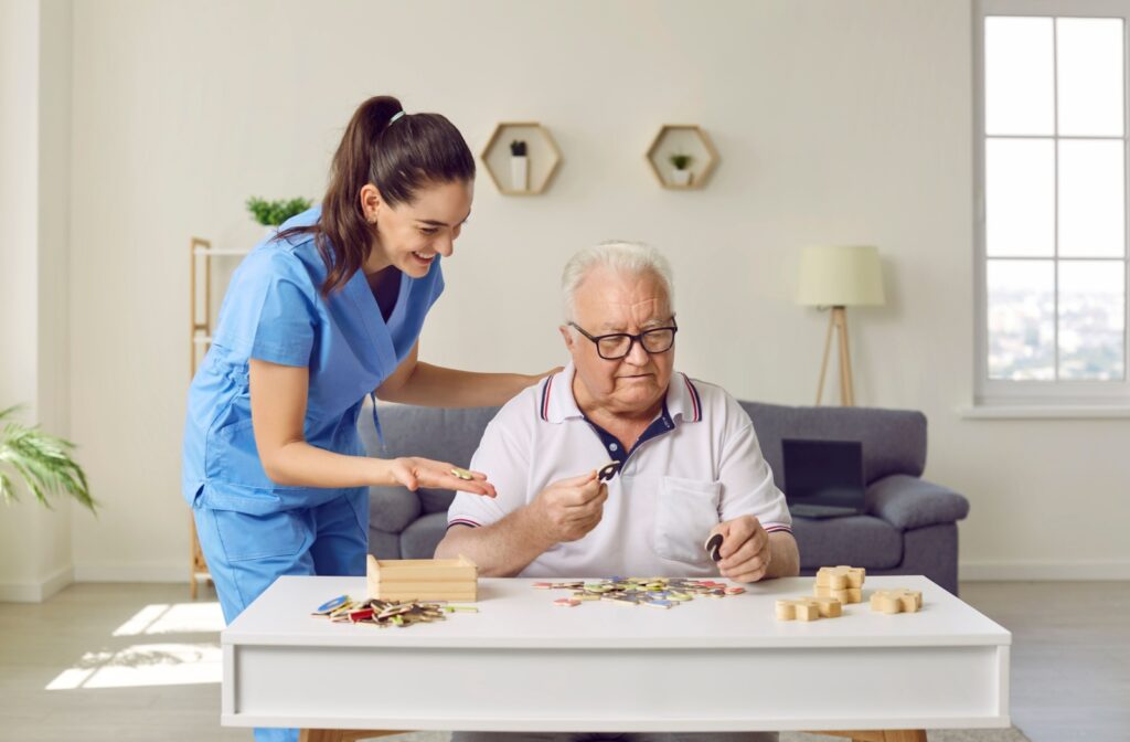 A memory care staff member is helping a resident solve a jigsaw puzzle.