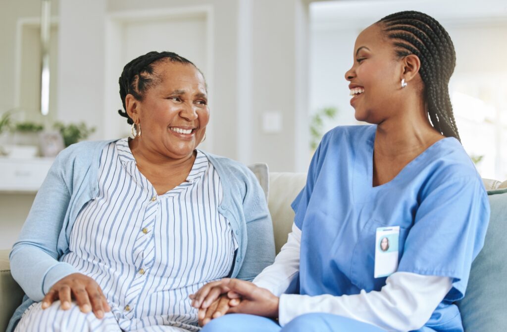 Senior sitting on a couch holding hands with a caregiver promoting trust safety and personalized care in assisted living communities