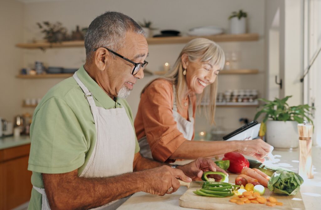 A couple happily cooking together in a bright kitchen, chopping fresh vegetables.