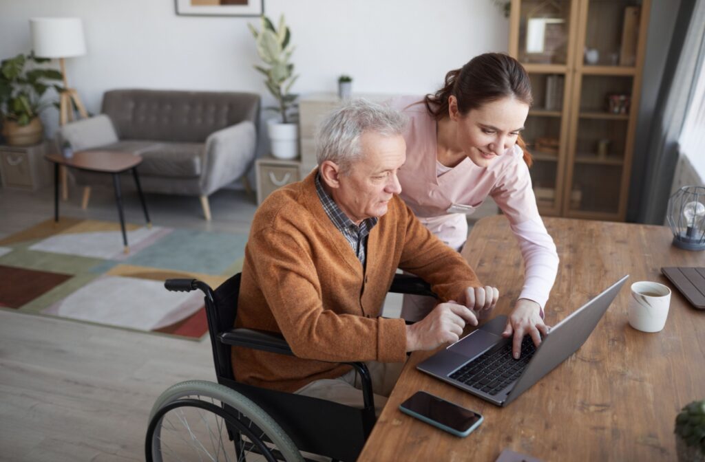 A nurse helps an older adult in assisted living with personal affairs on their computer