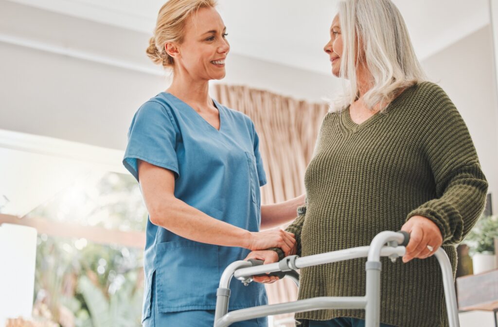 A kind nurse places a hand on a senior’s arm to comfort them while helping them relearn to walk after an accident