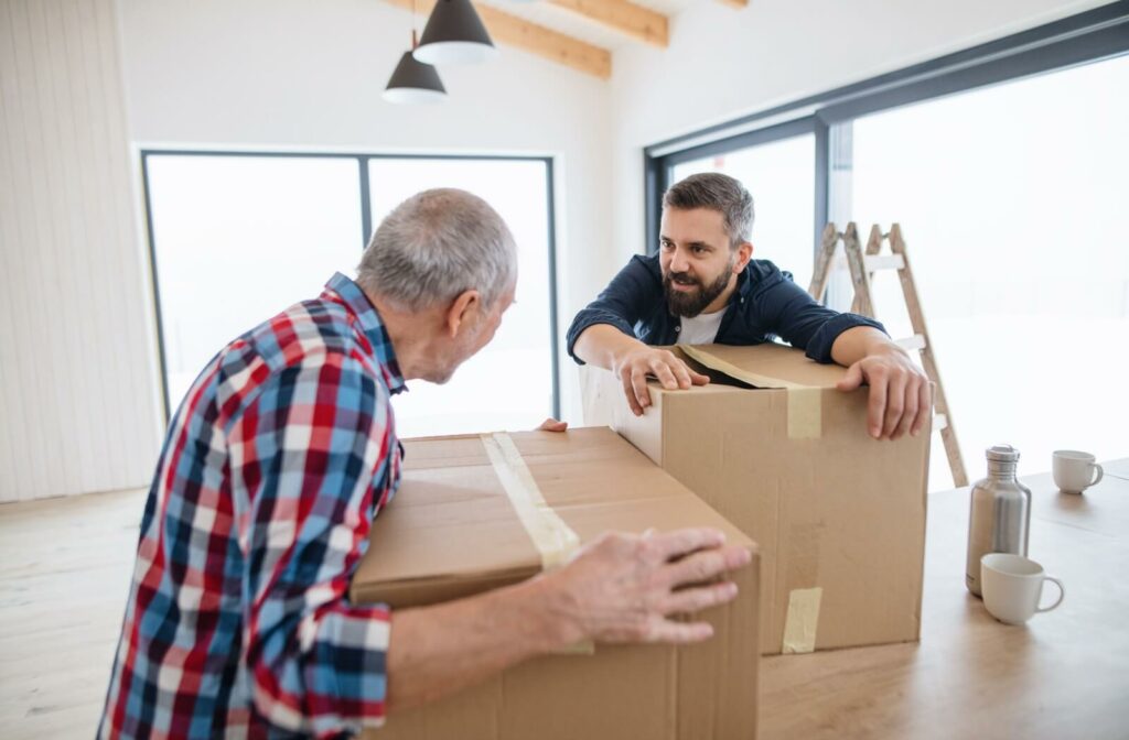 An adult helps their older parent move boxes from their old house in preparation for moving into assisted living